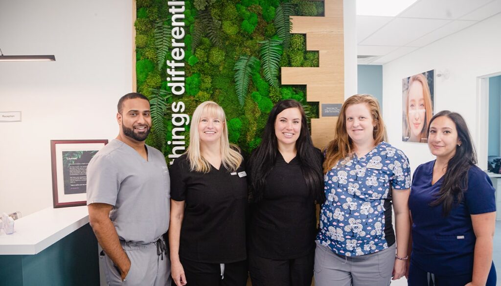 five people standing smiling at camera